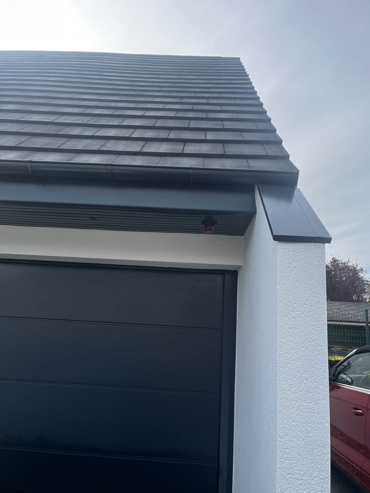 Angle de garage : enduit blanc, rive et porte anthracite