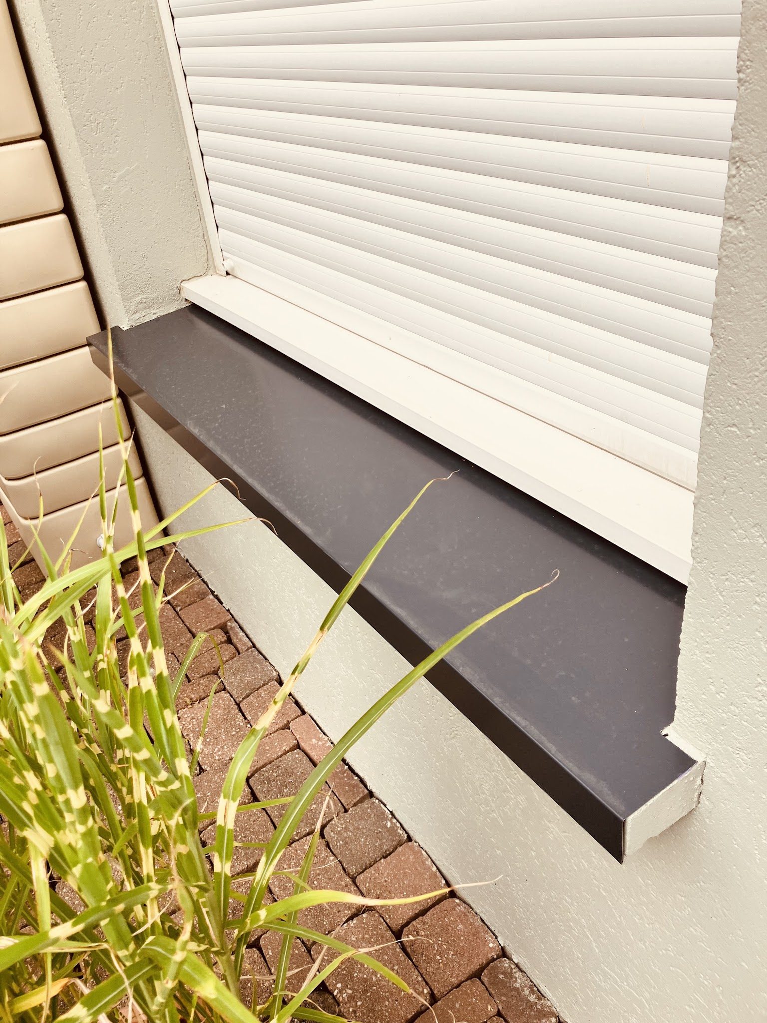 Appui de fenêtre anthracite sous un volet roulant blanc